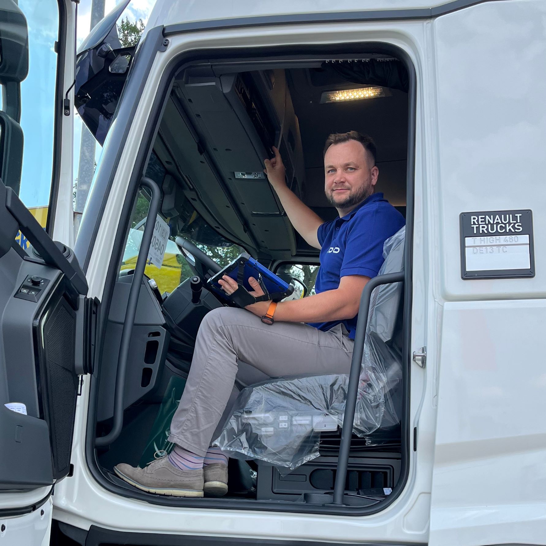 Photo of a VDO testimonial. A man sits with a tablet in a truck in the parking lot of a fleet and simultaneously operates his VDO DTCO 4.1 tachograph.